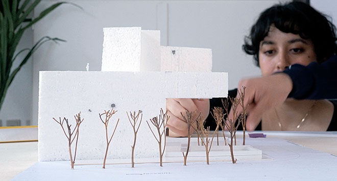 Kvinde arbejder med en miniature af et byggeri.