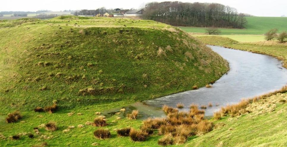 Voldsted Nordjylland reduceret Billede af Asdal voldsted med voldbanke og delvis vandfyldte grav omkring, ligger i grønne omgivelser