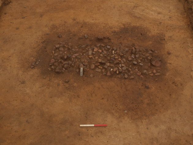 Billede af de fremgravede spor efter grav fra Enkeltgravskultur med en fin slebet økse i