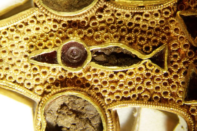 Nærbillede af guldfibulaen med den stiliserede fugl, hvor hoved og næb lavet af røde sten – muligvis stenarten granat