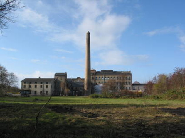 Foto af sukkerroe fabrikken i Holeby, hvor man ser fabrikken på afstand med den karkteristiske skårsten midt i billedet