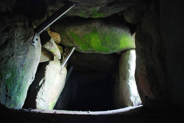 Foto fra jættestuens kammer, hvor sollyset bryder mørlet i en tynd stribe lys fra indgangen