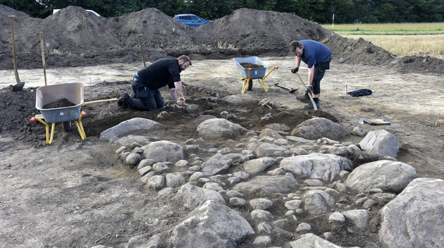 Foto af Arkæologerne i færd med afdækningen af de sidste rester af fundamentet til styltetårnet, der på billedet ligger synlig i udgravningen. 