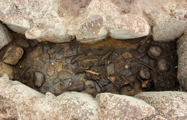 I bunden af gravkamret, der er omsat af sten, ligger de endnu ikke udgravede skeletrester af to børn og deres gravgaver