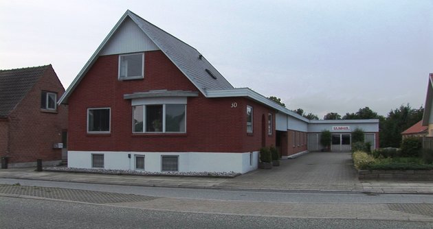 Foto af rød villa med tilbygget katakteristisk sidebygning, der tidligere blev brugt til tekstilfabrikation 