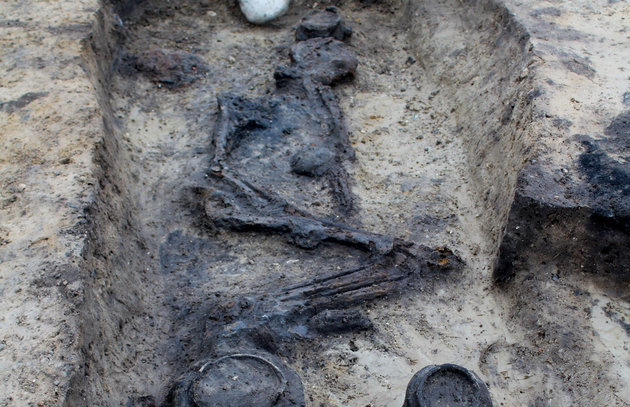 Foto af graven i den lyse undergrund, hvor skelettet ligger intakt med gravgaver.