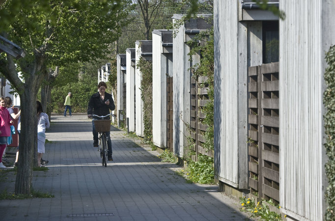 Cyklist og fodgængere på gang- og cykelsti ved gårdhavehuse.