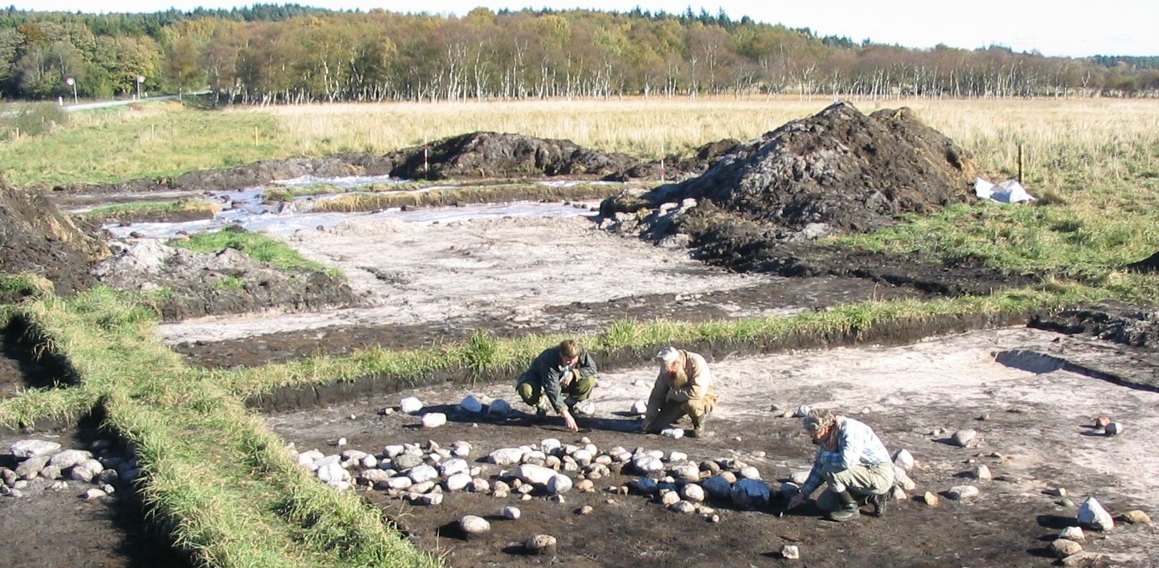 Stenlægningen fra ertebøllekulturen på Bølling Sø Vest I under udgravningen. På billedet ses Bo Bengtsen, Vibeke Juul Pedersen og Tinna Møbjerg. Foto: Jens Jørgen Kærgaard, Museum Midtjylland. Foto af udgravningsarbejdet.