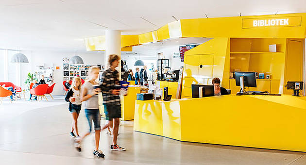 Tre børn og unge besøger biblioteket.