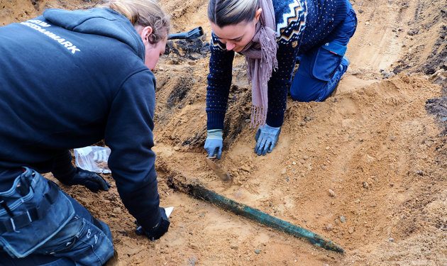 I det gule sand er arkæologer ved forsigtigt at fremgrave det grøniret sværd af bronze, der ligger helt intakt
