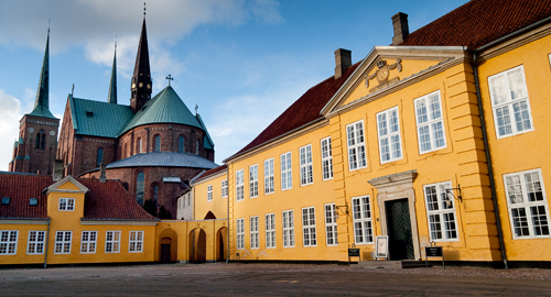 Det gule Roskilde Palæ med Roskilde Domkirke i baggrunden.