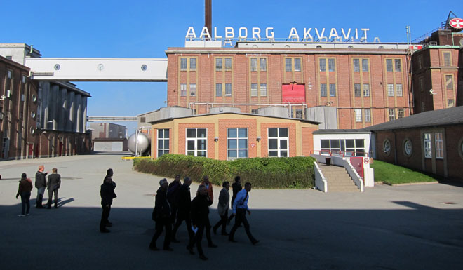 Aalborg Akvavits gamle fabriksbygninger, hvor Bygningssynets medlemmer ses i forgrunden.