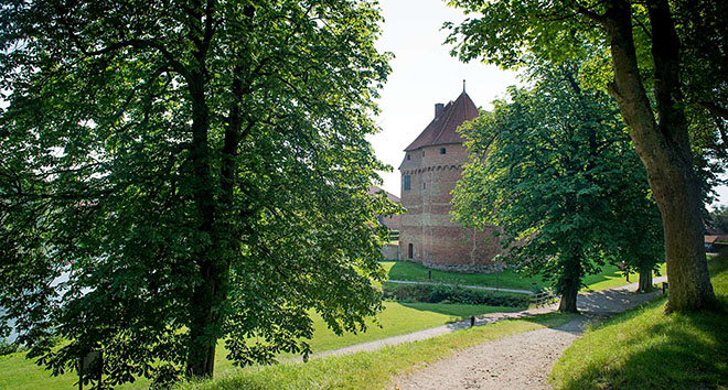 Nyborg Slot med grønne træer i forgrunden