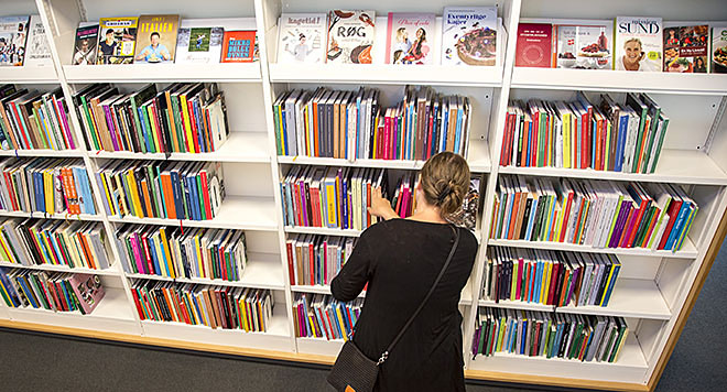 Kvinde ved biblioteksreol med bøger